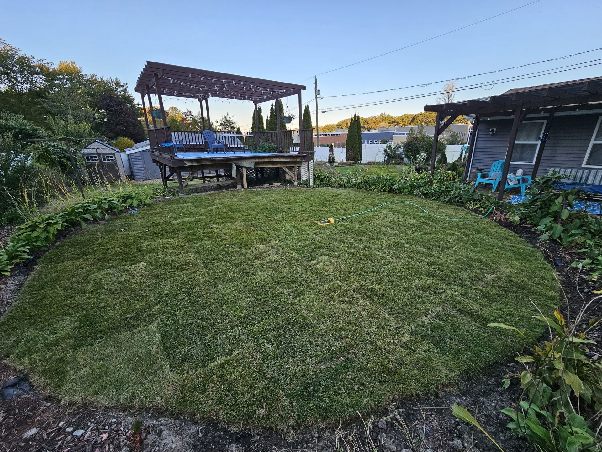 A lush green lawn with a gazebo in the background and a house in the background.