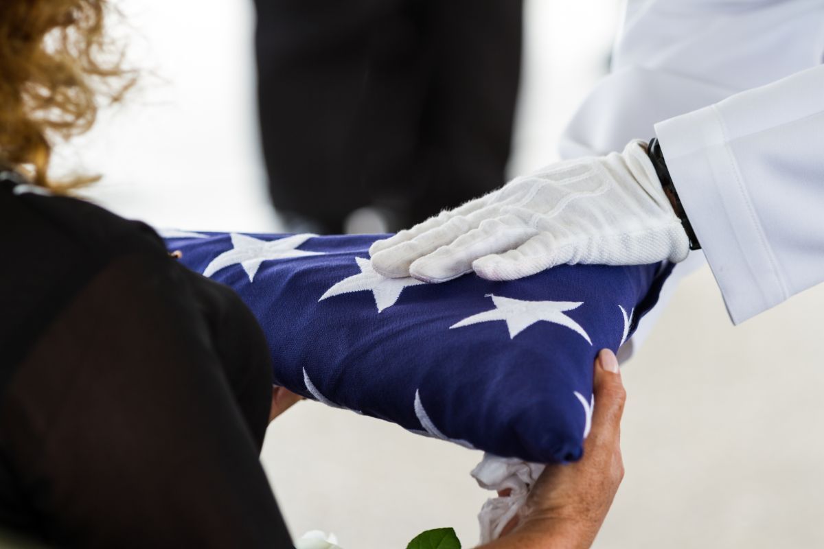 Gloved hands folding a folded U.S. flag during a ceremonial presentation