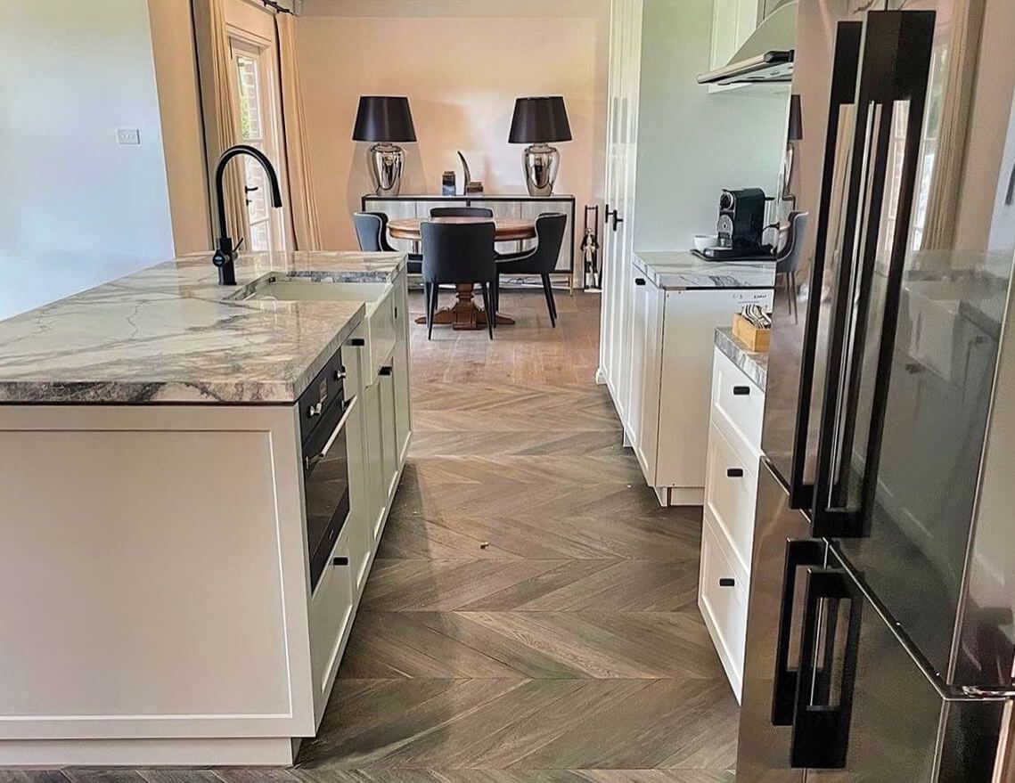 A Kitchen with White Cabinets, Stainless Steel Appliances, Granite Counter Tops, and A Dining Room in The Background — Tony Di Milia Flooring in Unanderra, NSW