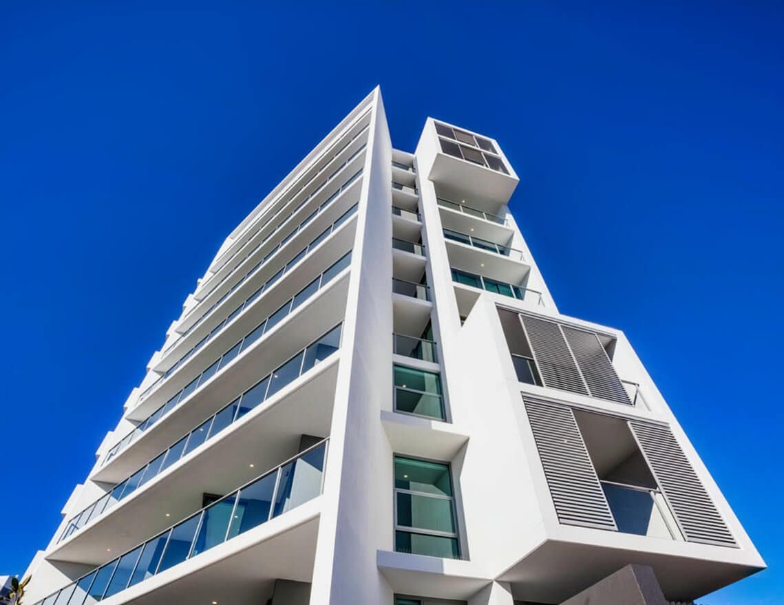 A Tall White Building with A Blue Sky in The Background — Tony Di Milia Flooring in Unanderra, NSW