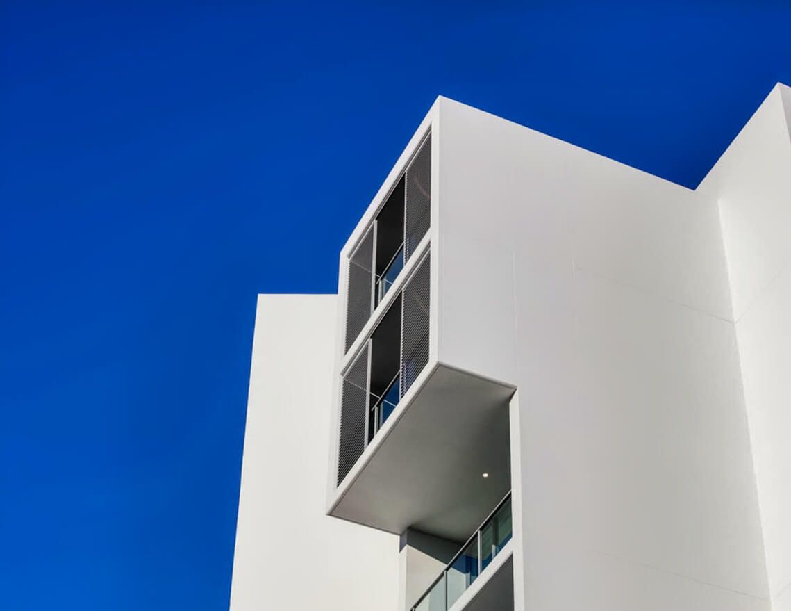 A White Building with Balconies Against a Blue Sky — Tony Di Milia Flooring in Unanderra, NSW