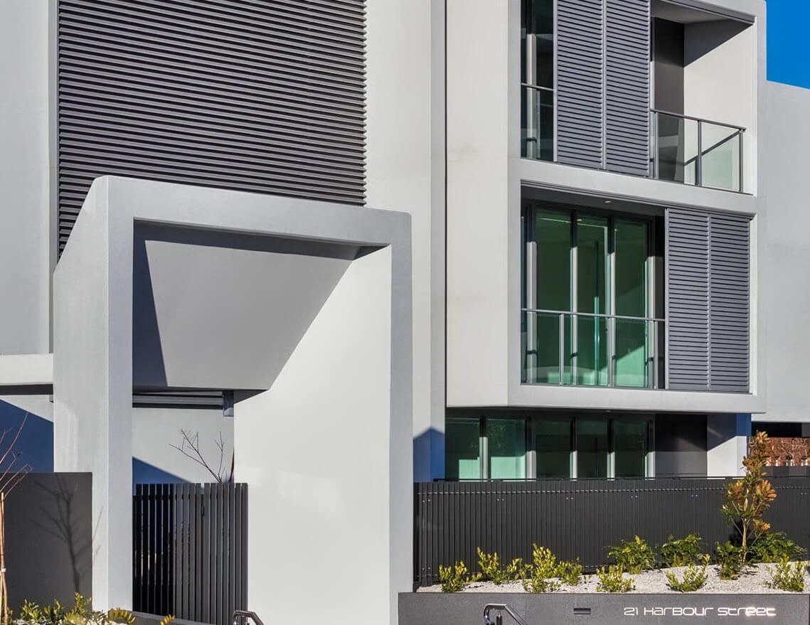 A White Building with A Black Fence in Front of It — Tony Di Milia Flooring in Unanderra, NSW