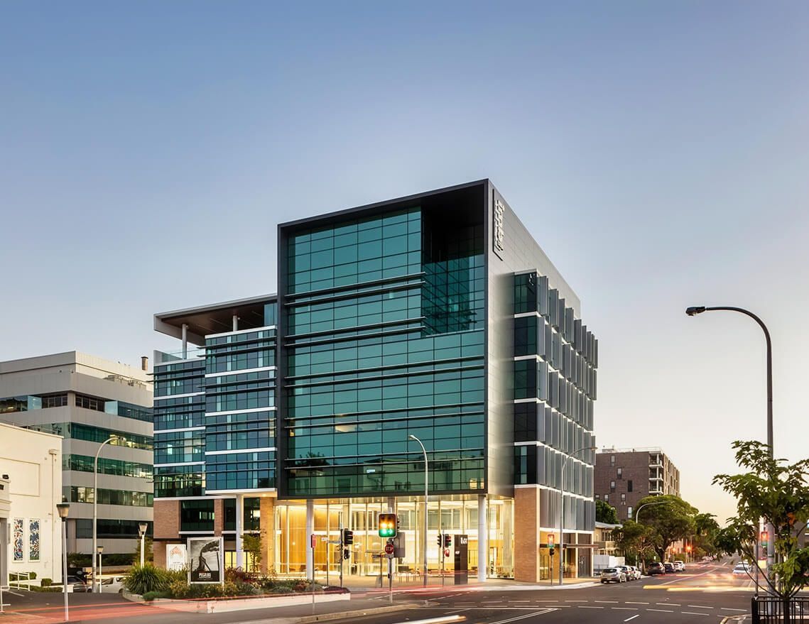 A Large Building with A Lot of Windows Is Sitting on The Corner of A City Street — Tony Di Milia Flooring in Unanderra, NSW