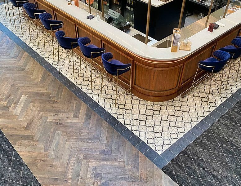 A Bar with A Wooden Counter and Blue Chairs in A Restaurant — Tony Di Milia Flooring in Unanderra, NSW