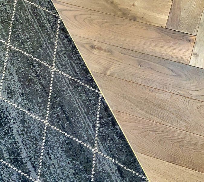 A Rug Is Sitting Next to A Wooden Floor — Tony Di Milia Flooring in Unanderra, NSW