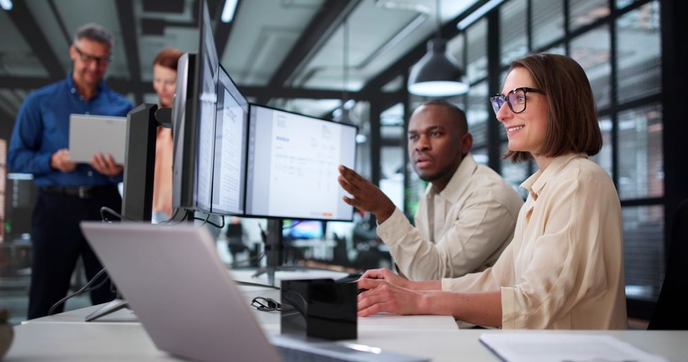 People collaborating around computer monitors in an office setting.