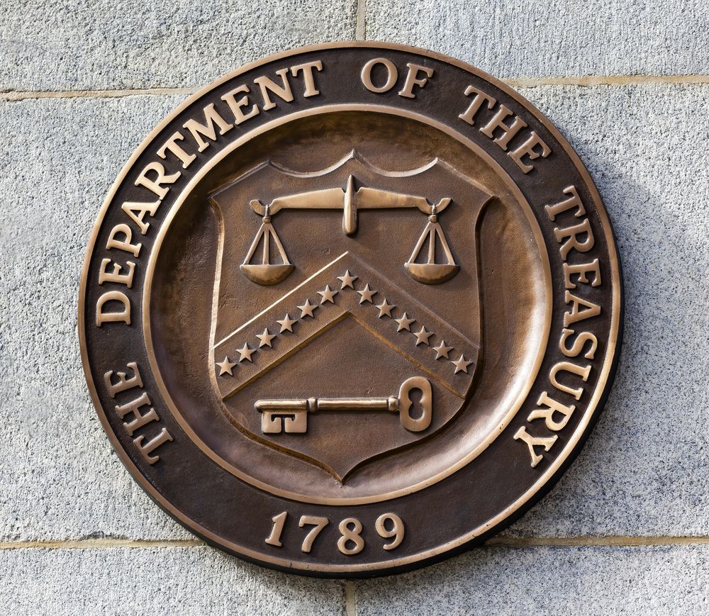 Seal of the U.S. Department of the Treasury, bronze, with scales, stars, and a key on a stone wall.