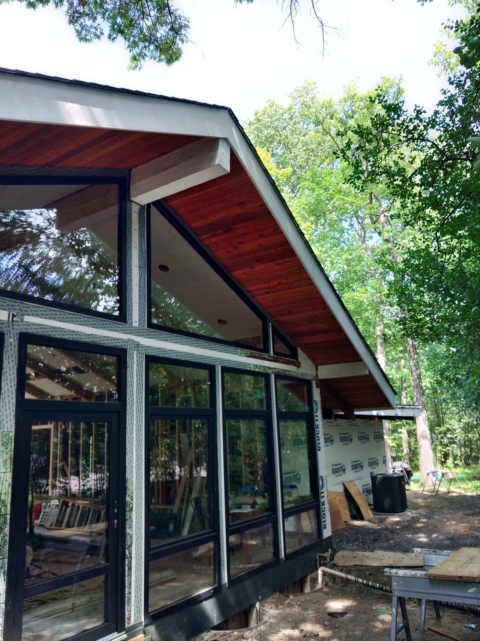 A house with a lot of windows and a wooden roof is being built.