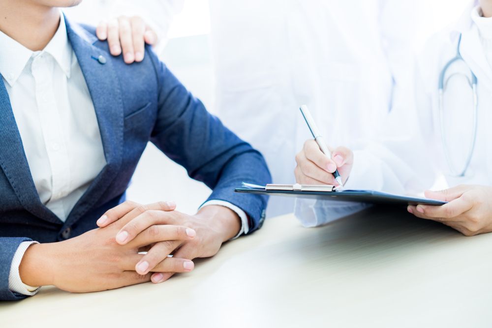 A Person In A Business Suit Sits At A Table While A Medical Professional — URO - Urology Specialists in Double Bay, NSW