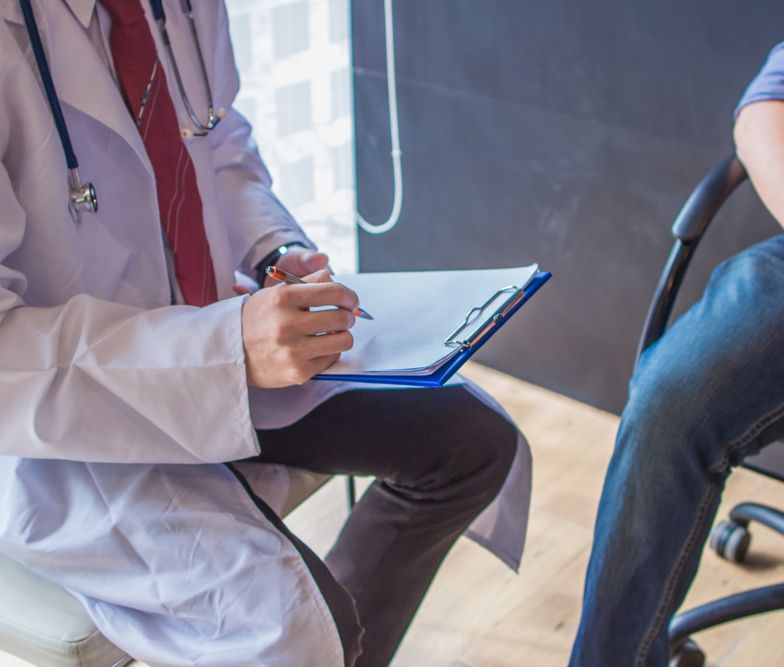 A Doctor In A White Coat Writes On A Clipboard — URO - Urology Specialists in Double Bay, NSW