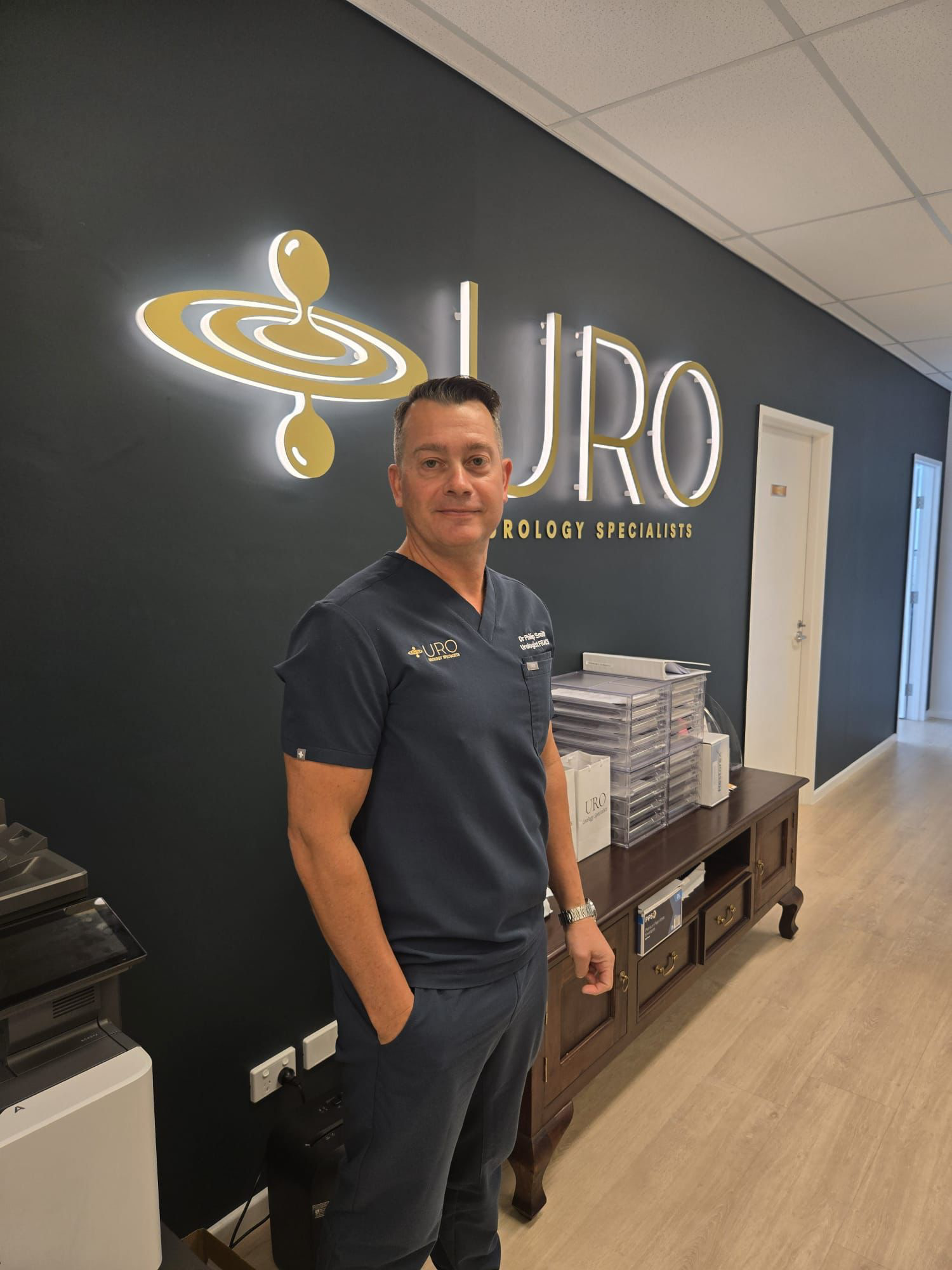 Man in a navy suit standing in a modern office — URO - Urology Specialists in Double Bay, NSW