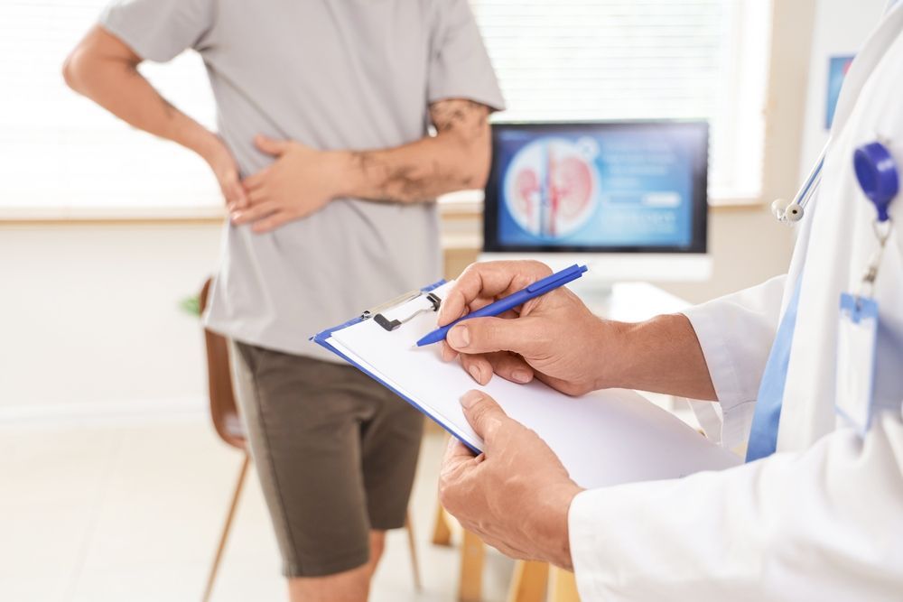 A Doctor in a White Coat Writes on a Clipboard as a Patient — URO - Urology Specialists in Double Bay, NSW 