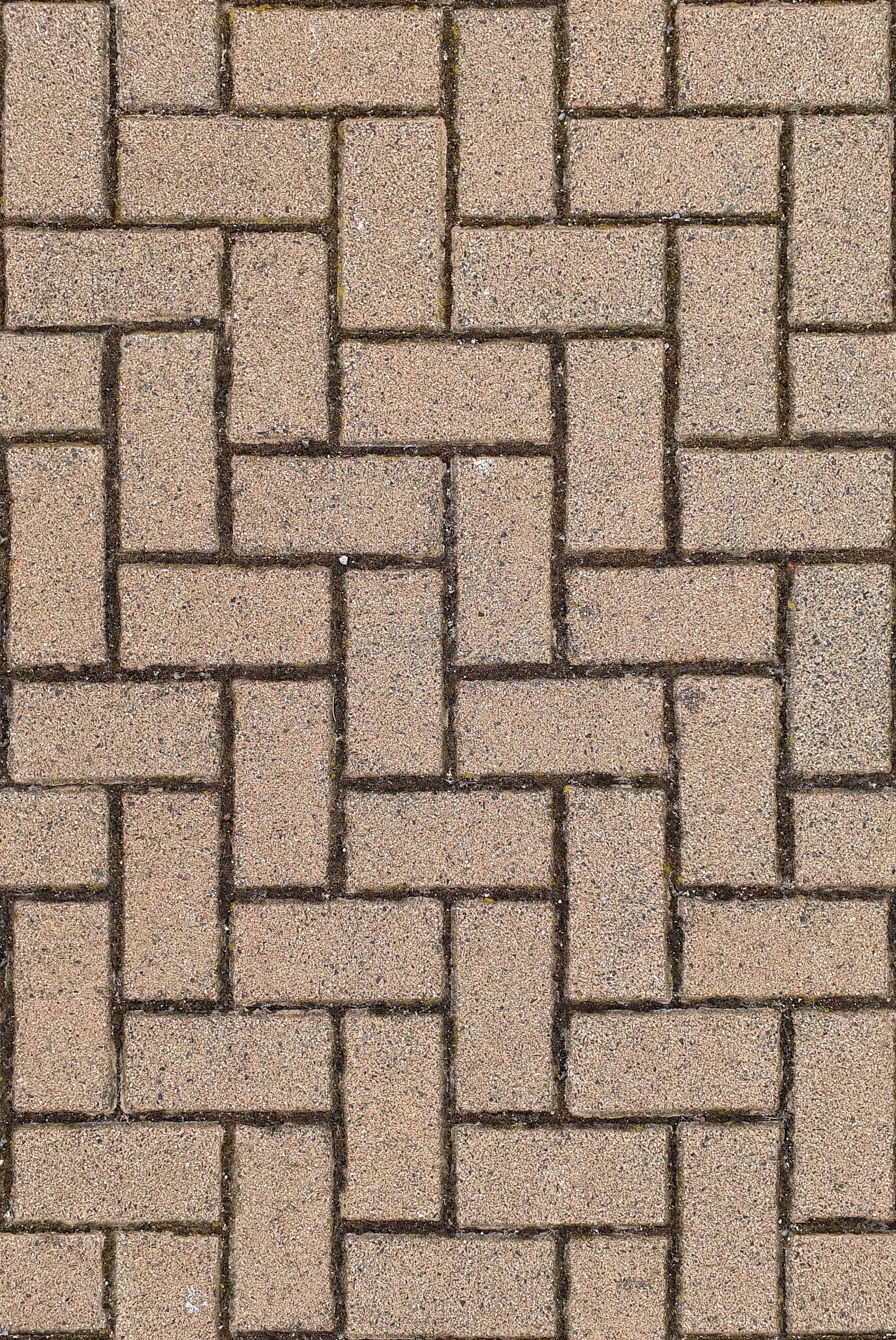 Tan and brown interlocking brick pavers in a repeating rectangular pattern.
