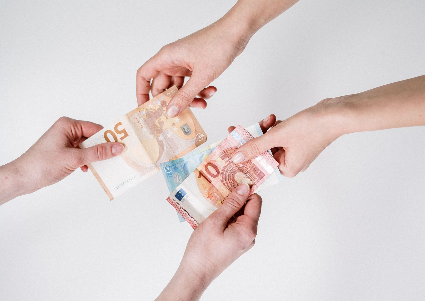 Hands exchanging Euro banknotes against a white background