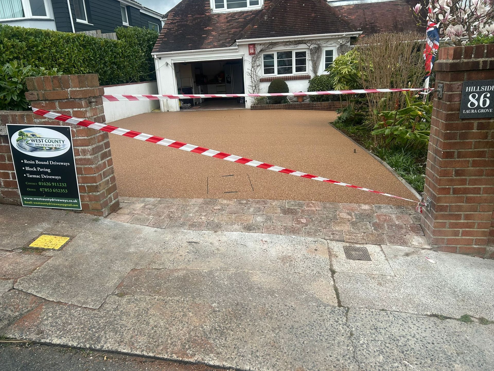 Front driveway blocked by red-and-white tape, leading to a house with a garage and parked car.