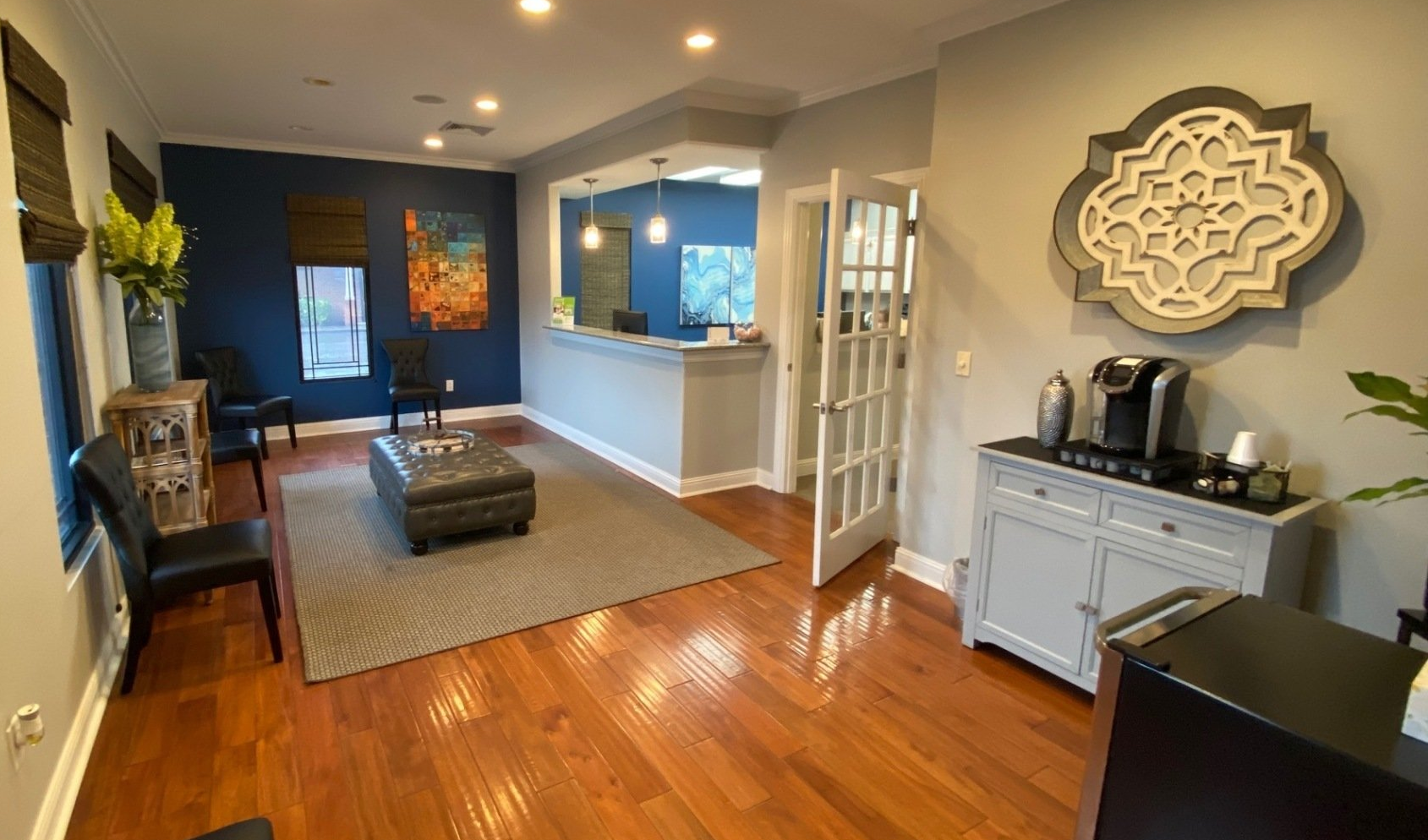 Waiting room with hardwood floors, coffee station, reception desk, and seating. Blue, gray and wooden tones. Waiting room with hardwood floors, coffee station, reception desk, and seating. Blue, gray and wooden tones.