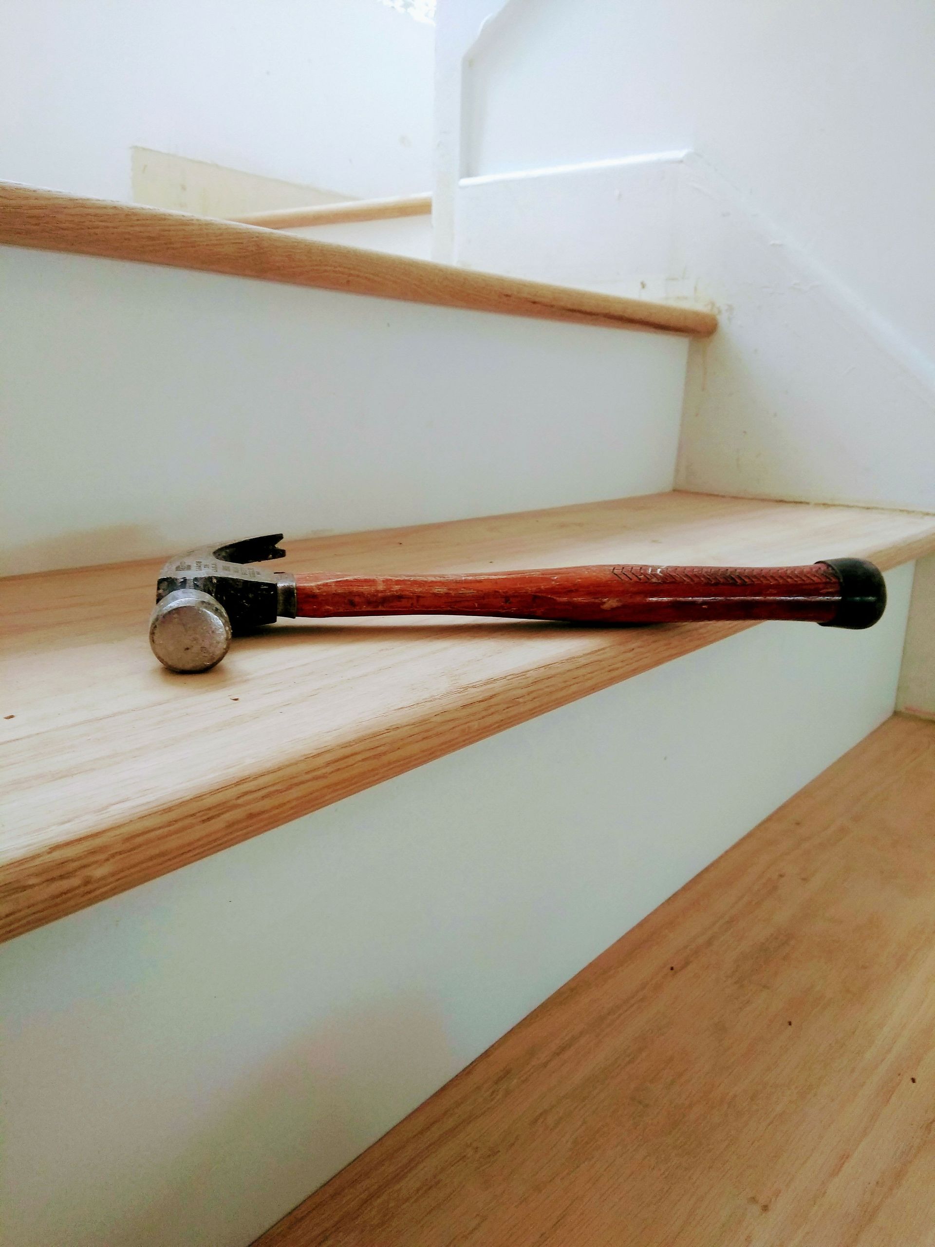 A hammer is laying on a wooden staircase