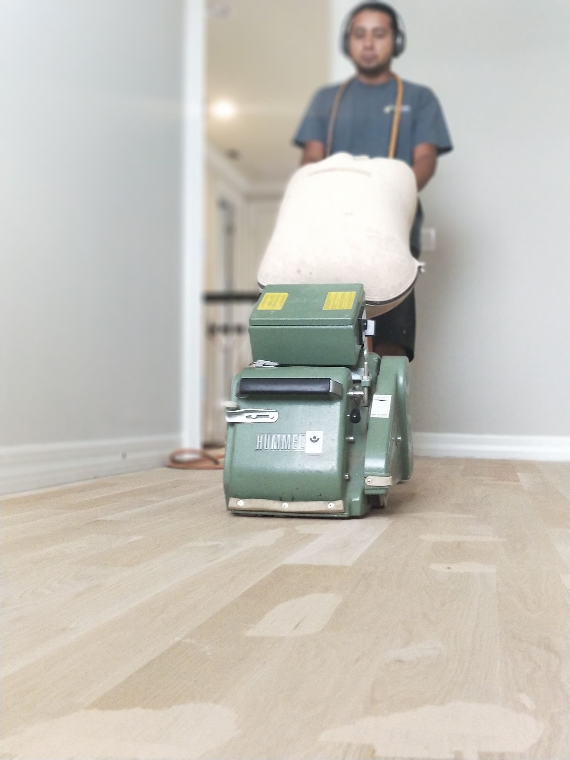 A man is using a machine to sand a wooden floor