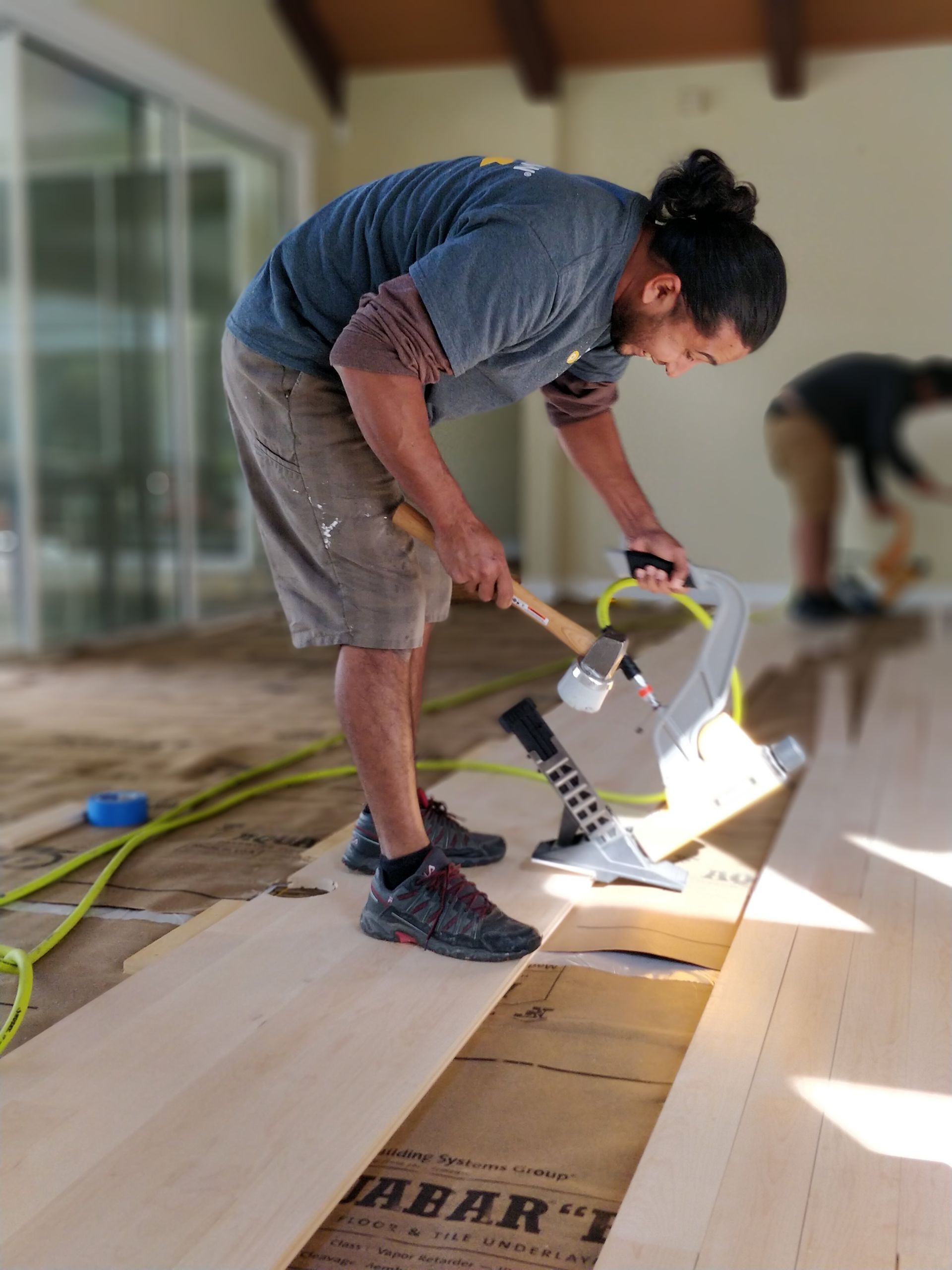 A man is working on a wooden floor with a hammer