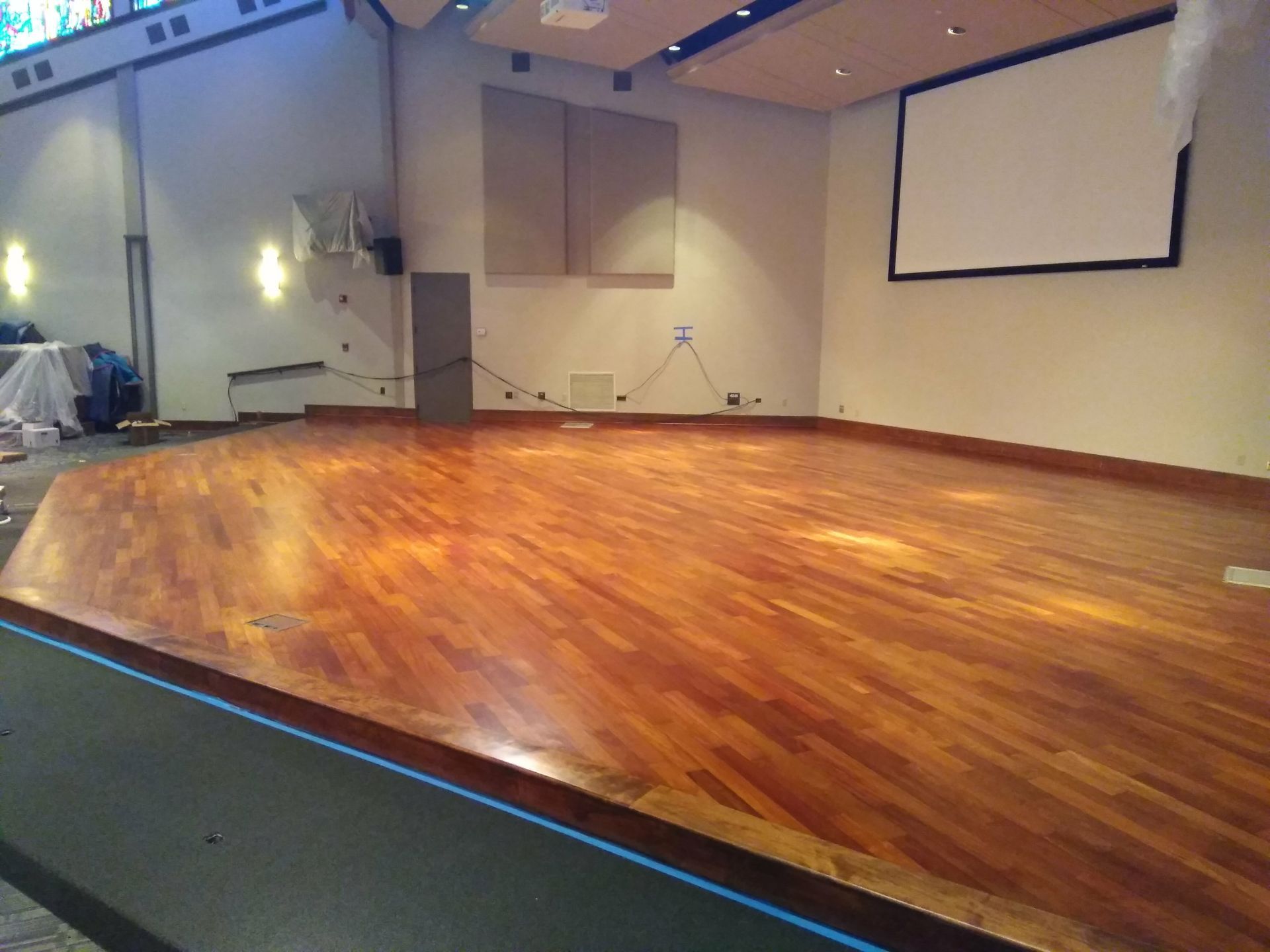 A large room with a wooden floor and a projector screen