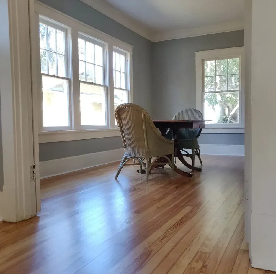 A dining room with a table and chairs and lots of windows
