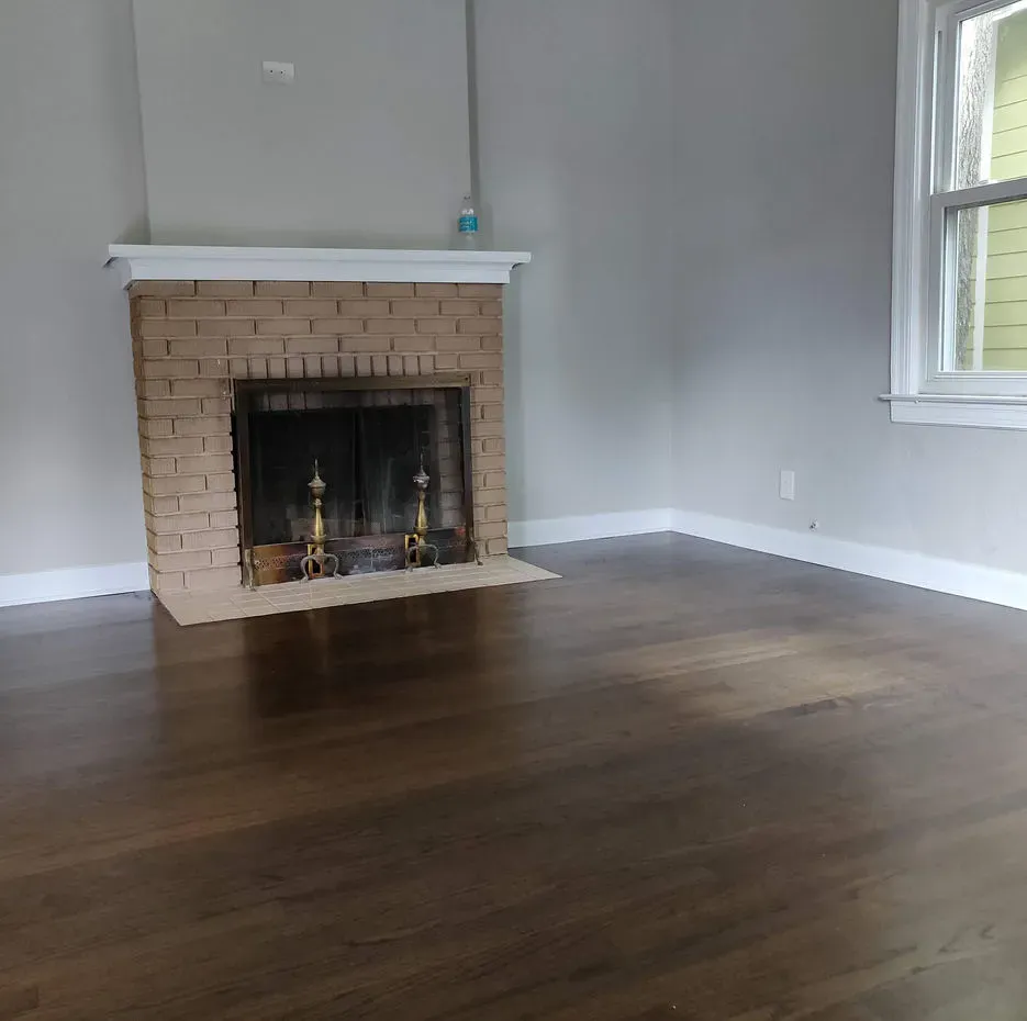 An empty living room with a fireplace and a window