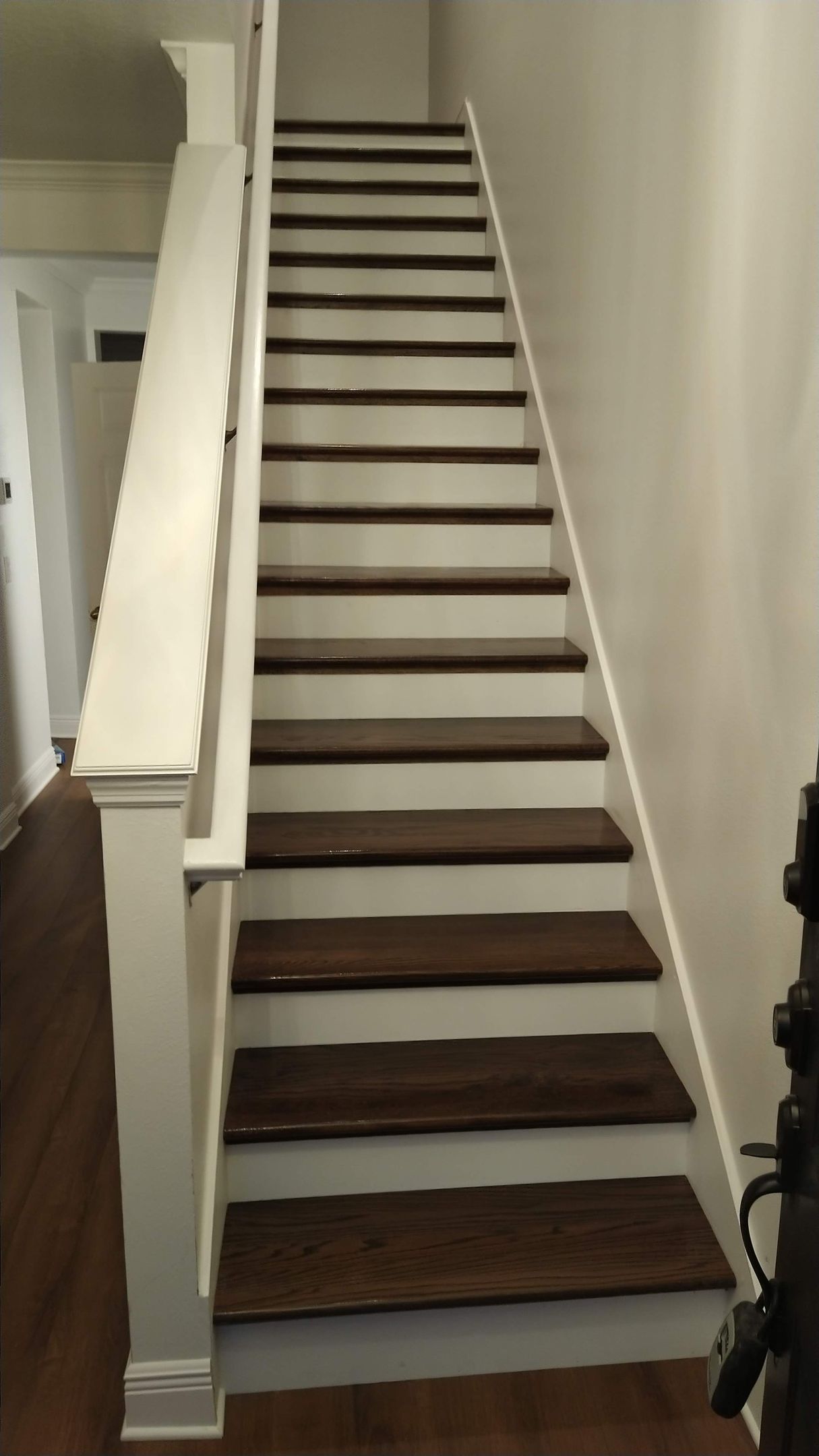 A staircase with wooden steps and a white railing in a hallway