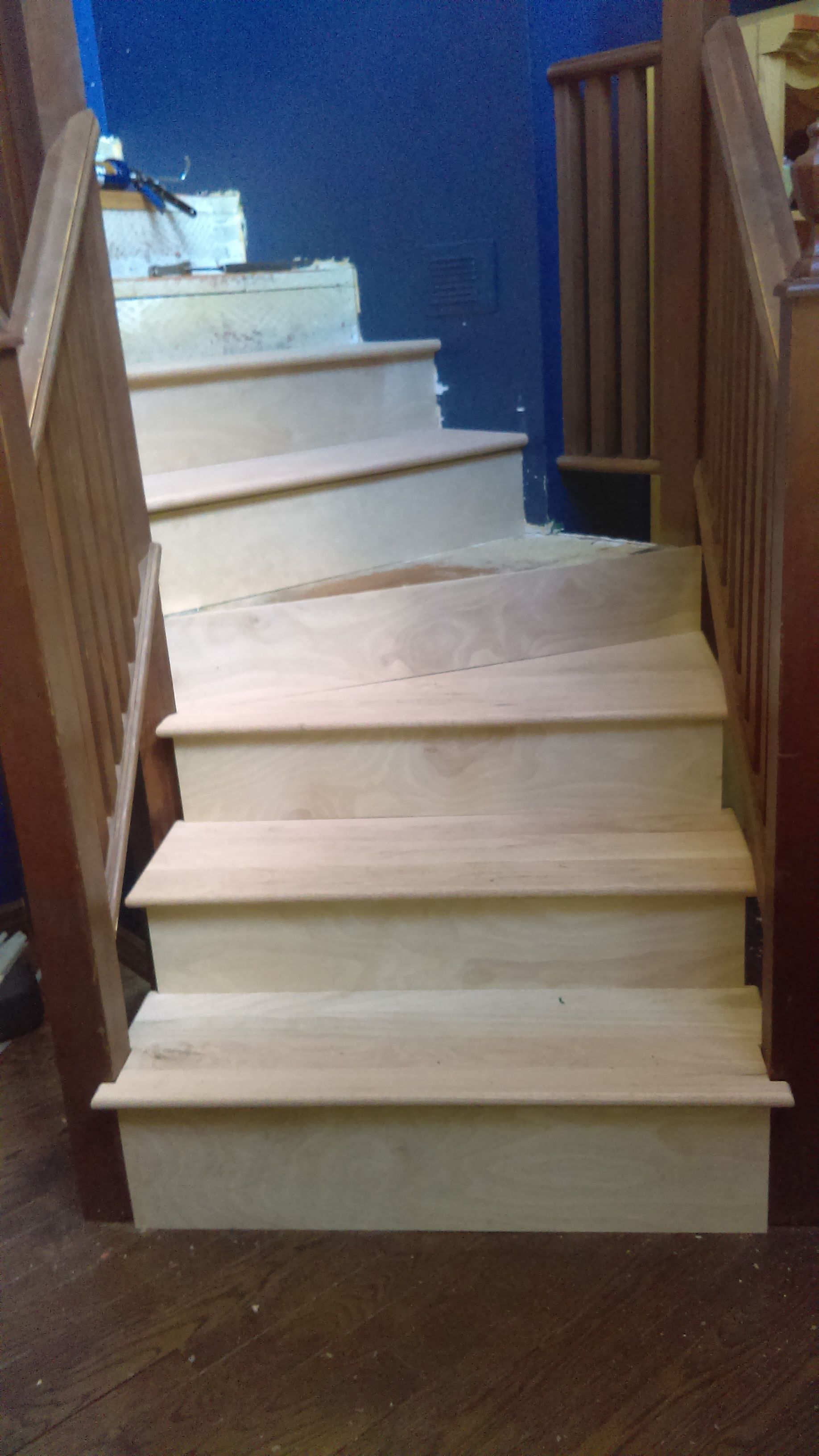 A set of wooden stairs with a wooden railing in a room