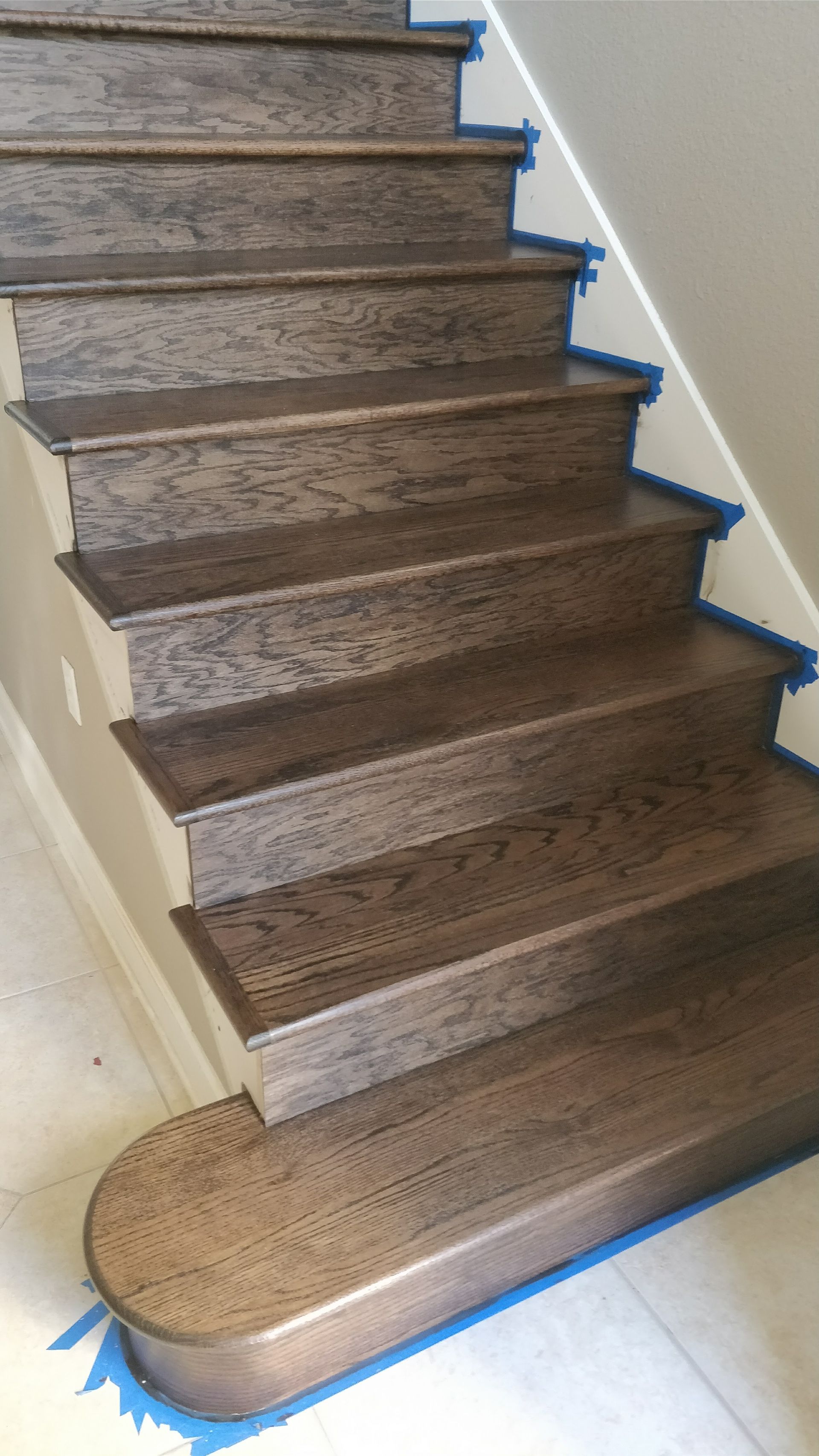 A close up of a wooden staircase with blue tape on the steps