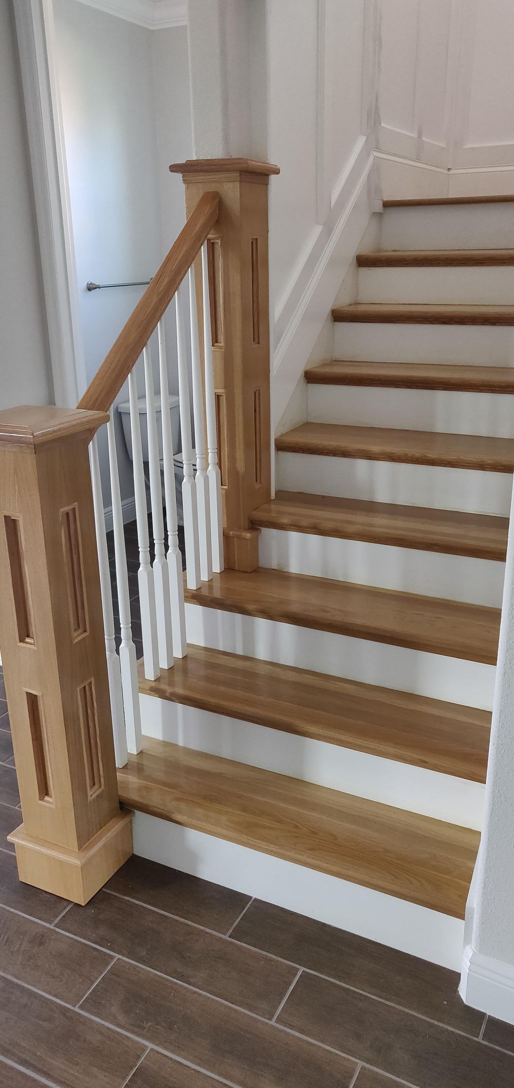A wooden staircase with white steps and a wooden railing