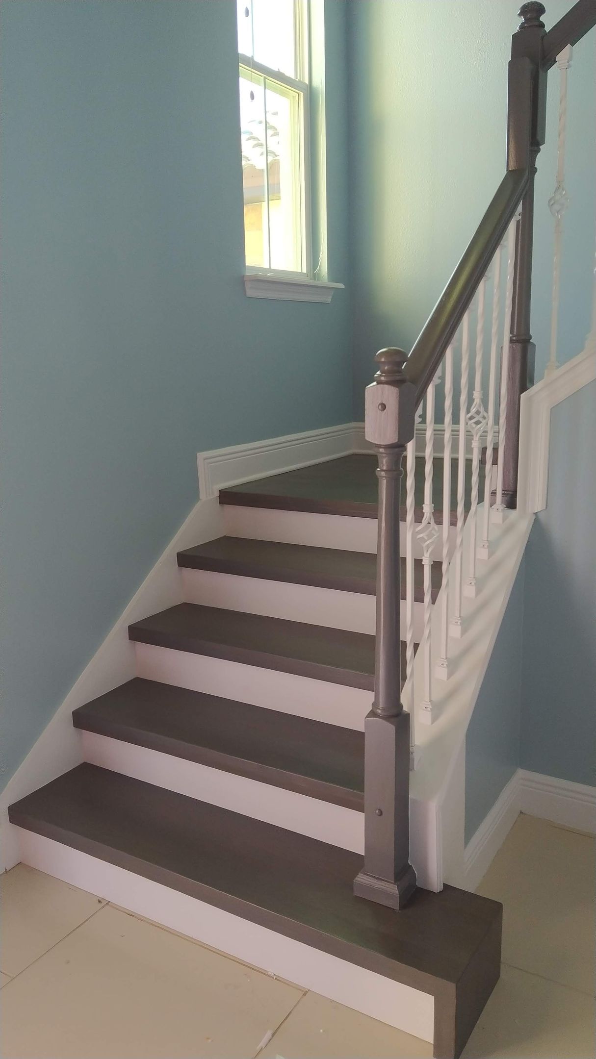 A staircase with a wooden railing and steps in a room with blue walls