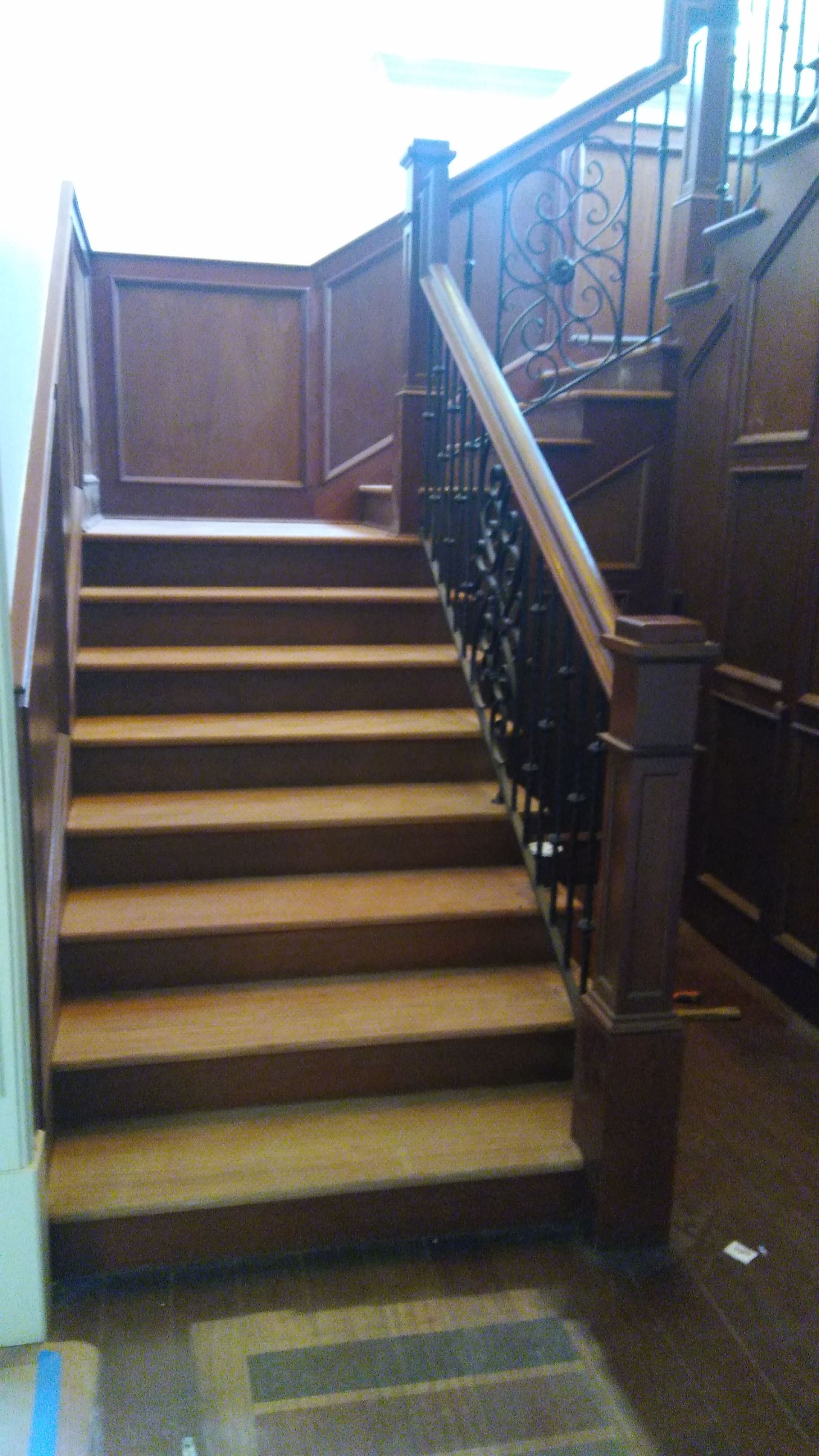 A wooden staircase with a wrought iron railing in a building