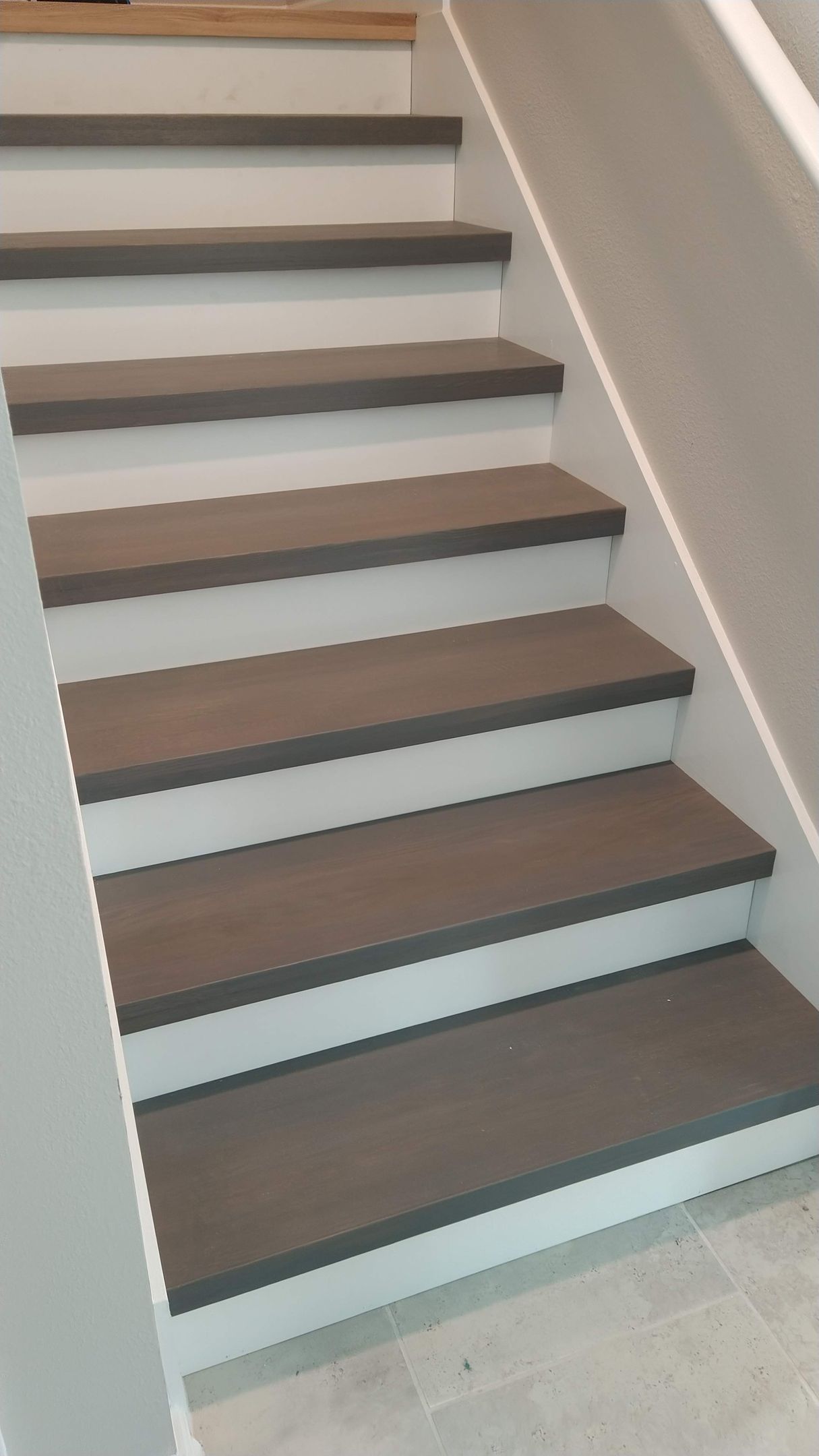A set of stairs with gray steps and white railing