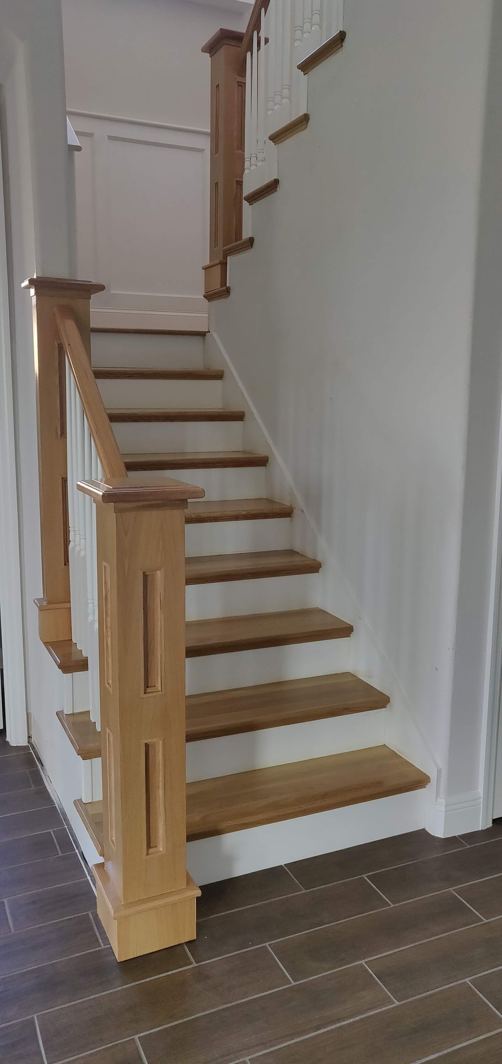 A wooden staircase with white steps and a wooden railing in a house