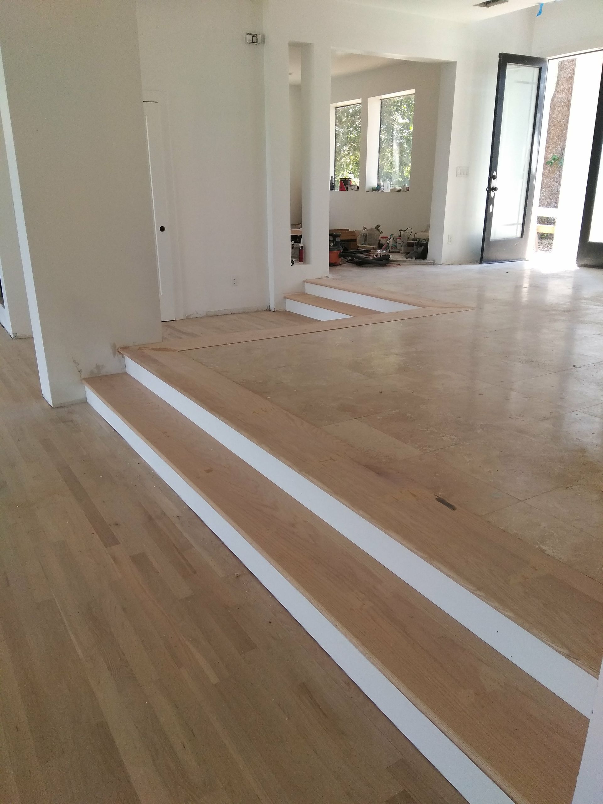 A living room with wooden floors and white stairs