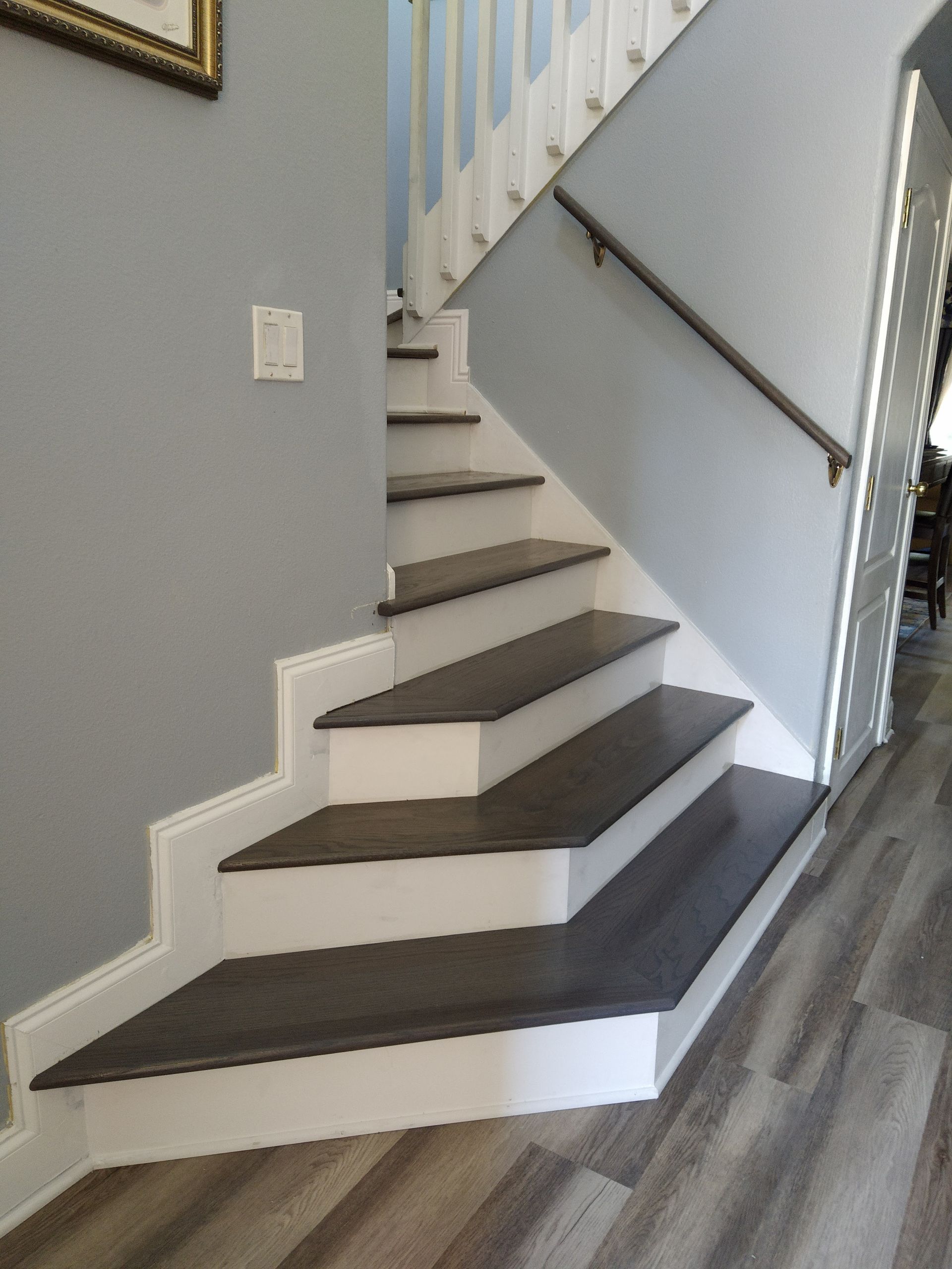 A staircase with wooden steps and a white railing in a hallway