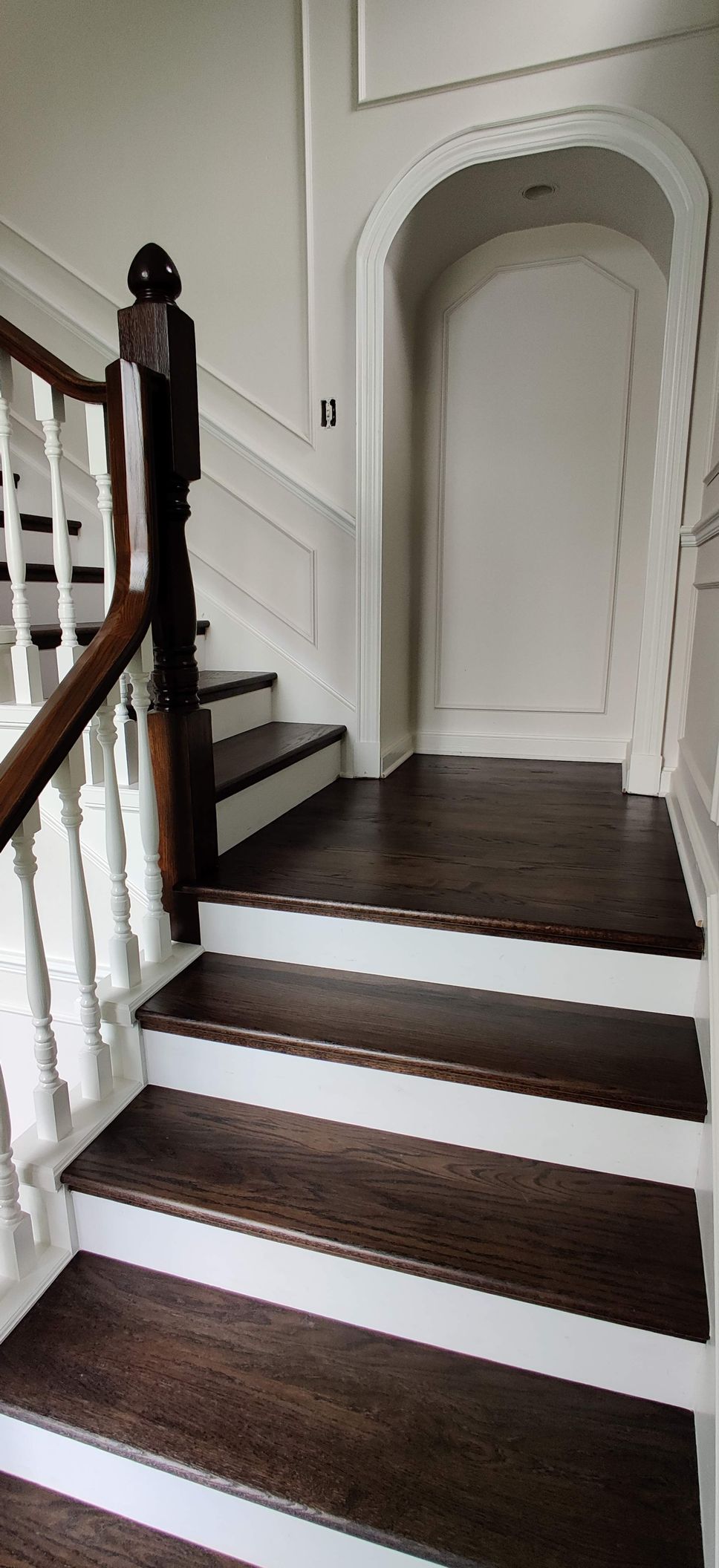 A wooden staircase with white steps and a wooden railing in a house