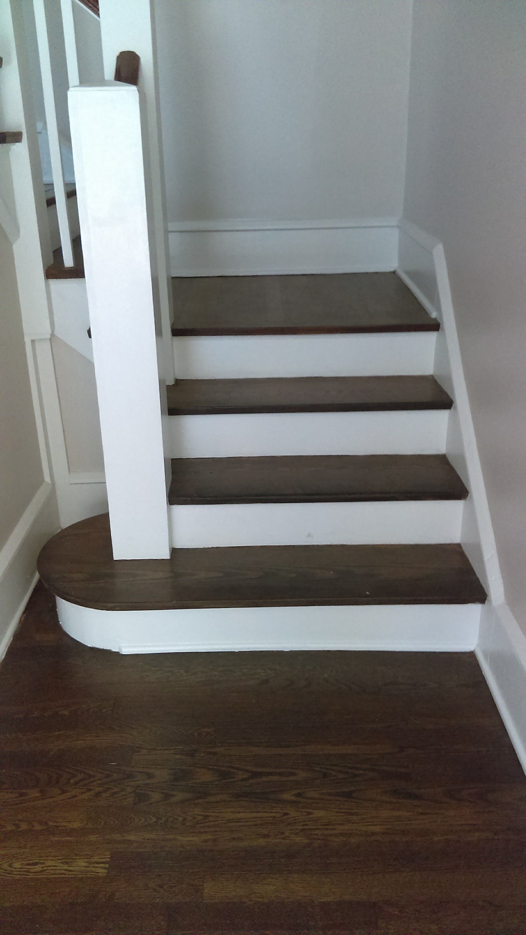 A close up of a staircase with wooden steps and a white railing