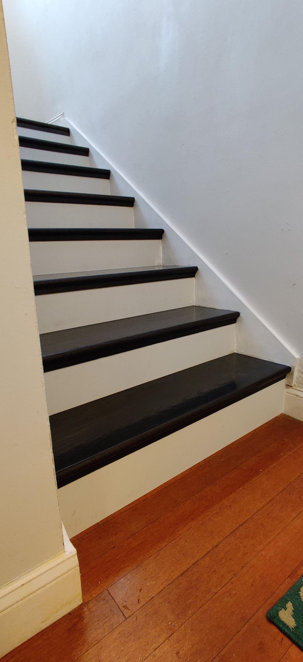 A set of white stairs with black steps and a wooden floor