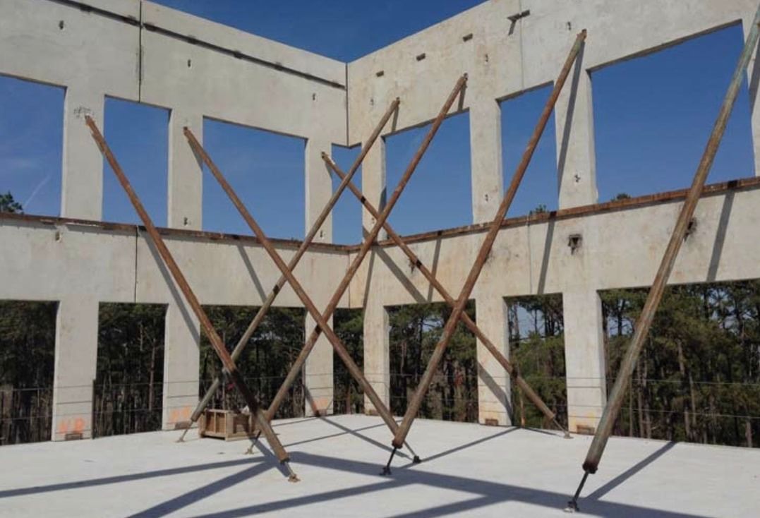 A building under construction with a lot of wooden sticks in front of it