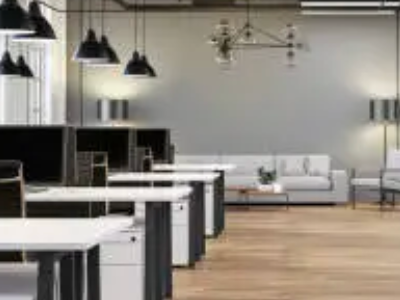 A row of desks in an office with a living room in the background.