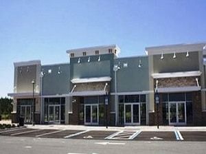 A large building with a lot of windows and a parking lot in front of it.
