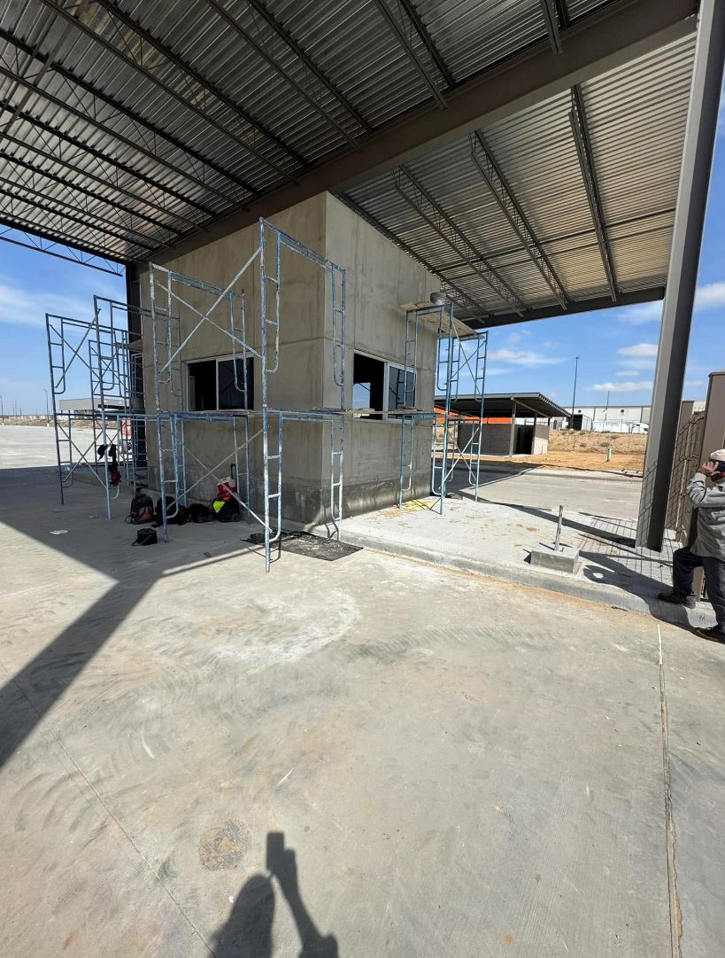 A man is standing in front of a building under a canopy.