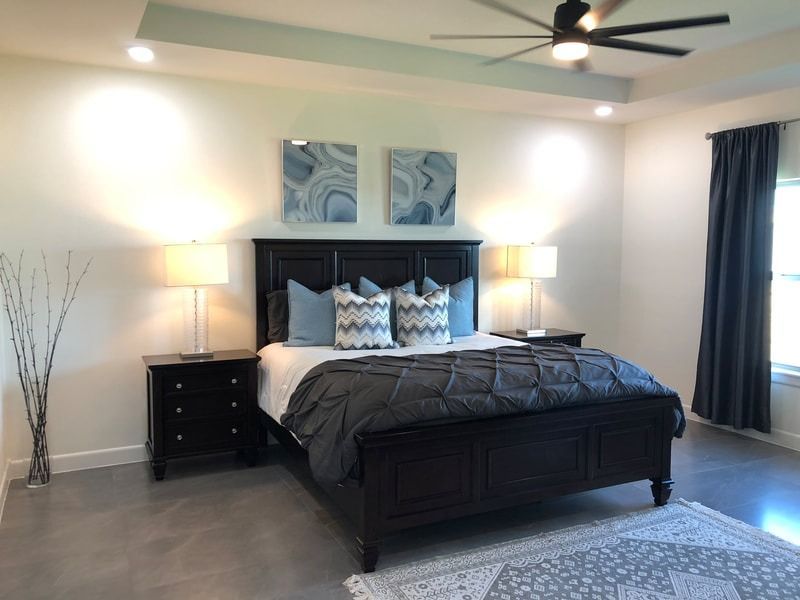 A bedroom with a bed , nightstands , lamps and a ceiling fan.