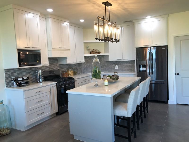 A kitchen with white cabinets , stainless steel appliances , and a large island.
