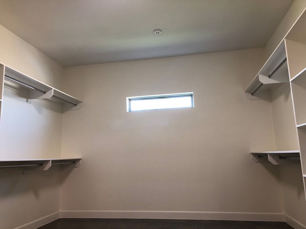 An empty walk in closet with shelves and a window.