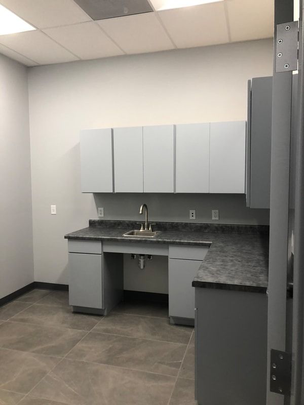 An empty kitchen with gray cabinets and a sink