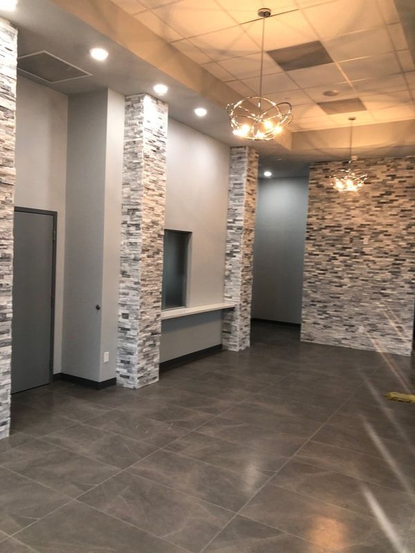 A large empty room with a brick wall and a chandelier hanging from the ceiling.