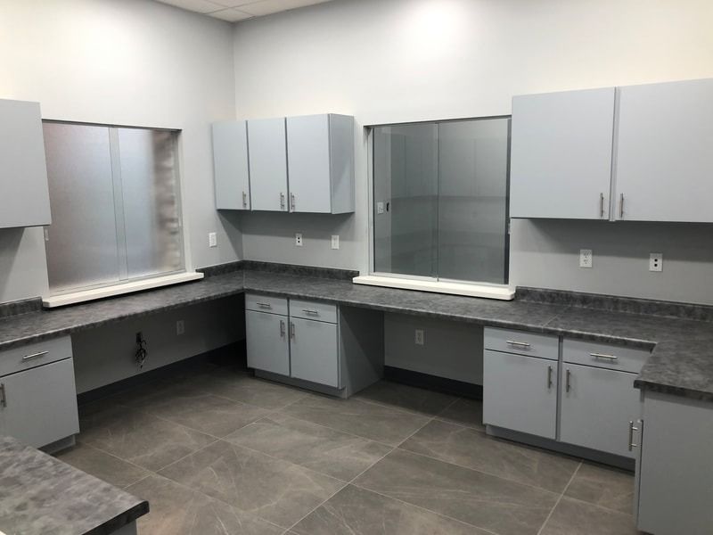 A kitchen with gray cabinets and granite counter tops.