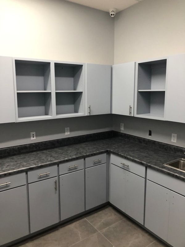A kitchen with white cabinets , granite counter tops , and a sink.